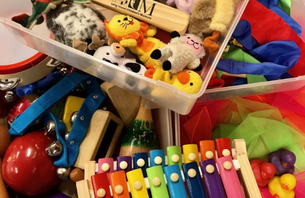 Containers filled with finger puppets, scarves, rubber ducks and musical instruments. 
